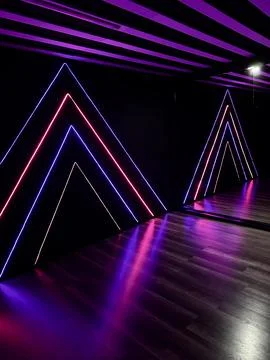 Futuristic interior with glowing neon triangle light installations Stock Photos