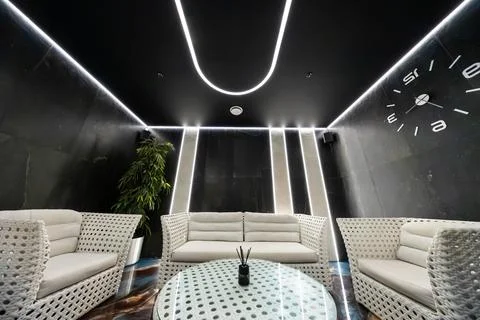 Futuristic lounge with woven sofas, neon accents, and glass table Stock Photos