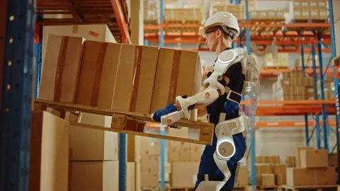 Futuristic Modern Warehouse Worker with Exoskeleton Suit Moves Stock Footage 141577132