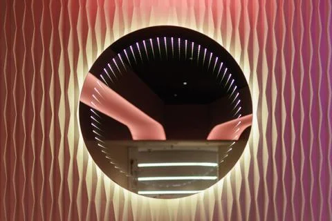 Futuristic round infinity mirror glows on pink textured wall, creating stylis Stock Photos