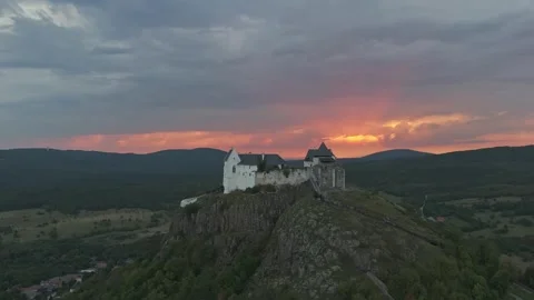 Füzér Castle above forested hills at dusk in a panoramic drone orbit shot Stock Footage 340106893