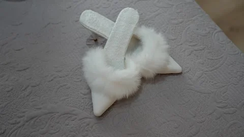 Fuzzy white high heels placed on a textured surface in a well-lit room during Stock-Footage 330924384