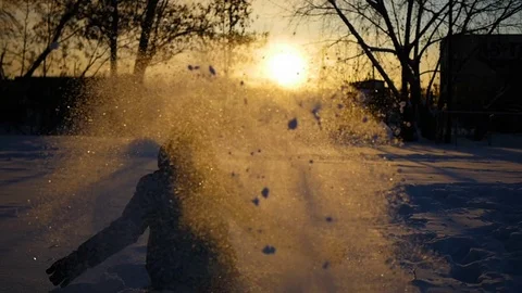 G child throwing snow over himself and enjoys it in winter park at sunset 库存影片 69860799