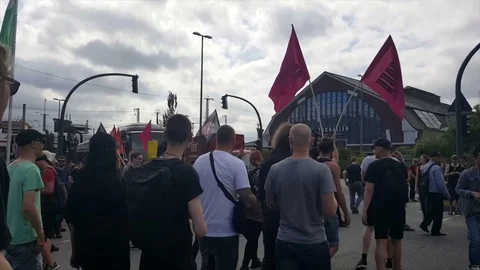 G20 demonstration Hamburg 2017, demonstrators march, shot from back, cloudy sky Stock Footage