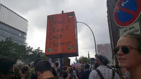 G20 demonstration Hamburg, demonstrators back shot, black block go home sign Видео 77702439