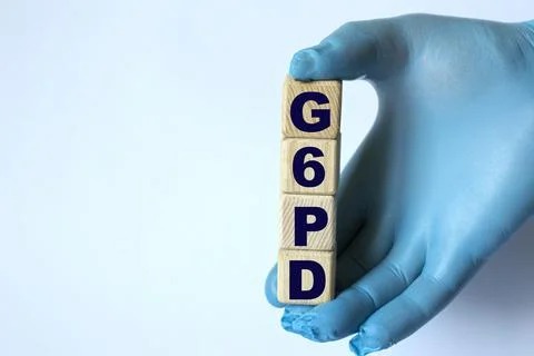 G6PD is an acronym on cubes held by a hand in a blue glove Stock Photos