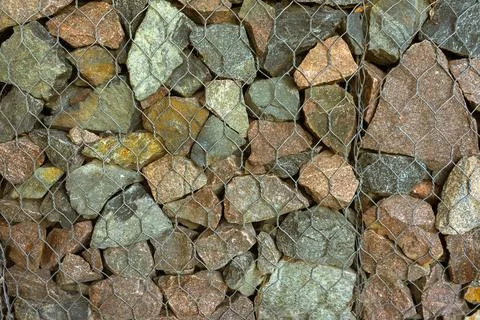Gabion, texture, background. Wall made of natural rocks and metal fences. Stock Photos