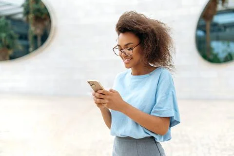 Gadget, wireless technology. Successful African American young curly woman with Stock Photos