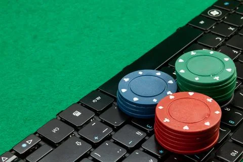 Gambling chips on computer keyboard on green background Stock Photos