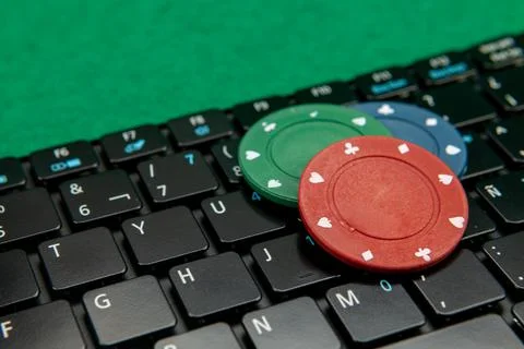 Gambling chips on computer keyboard on green background Stock Photos