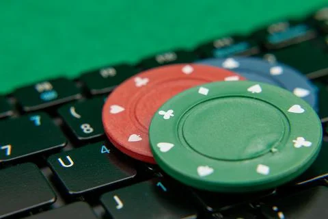 Gambling chips on computer keyboard on green background Stock Photos