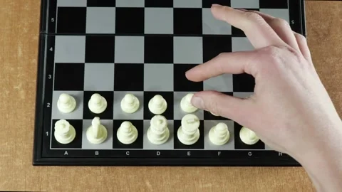 A game of chess. A woman's hand moves a chess piece on a black board. Stock Footage 145385597