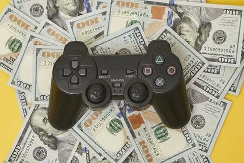Game console controller and pile of money Stock Photos