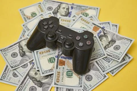 Game console controller and pile of money Stock Photos