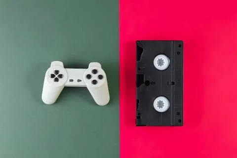 Game controller and cassette tape on colored background Stock Photos