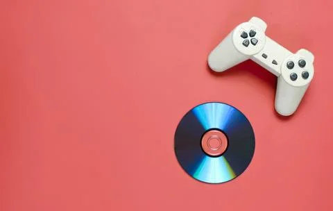Game controller and cd on pink background Stock Photos
