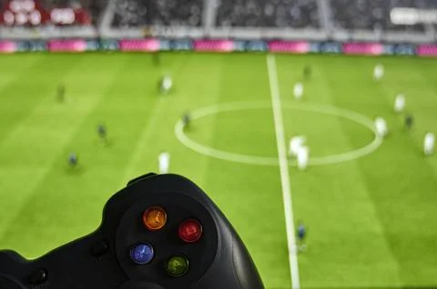 Game controller in front of a screen with a soccer video game Stock Photos