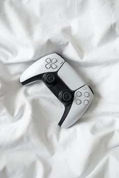 Game controller, lying on white sheets of bed at home. Stock Photos