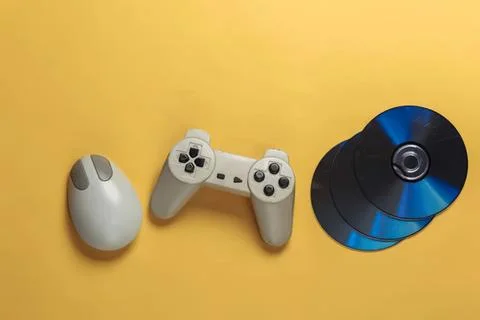 Game controller mouse and cds on yellow background Stock Photos