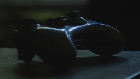 Game Controller in Shadow Resting on a Wooden Table Close Up Stock Footage 113519579