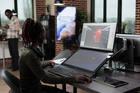 Game developer sitting in creative agency office workspace while designing game Stock Photos