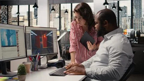 Game developers working on futuristic video game on computer Stock Photos