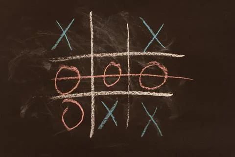 A game of tic-tac-toe drawn in chalk on a blackboard, a concept. Stock Photos