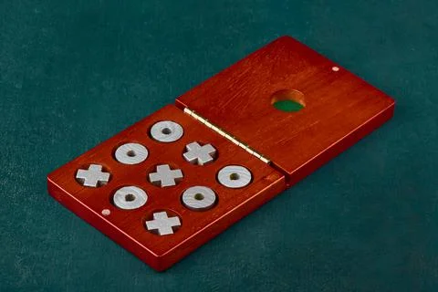 Game of Tic Tac Toe or Noughts and Crosses in a wooden box on a green backgro Stock Photos