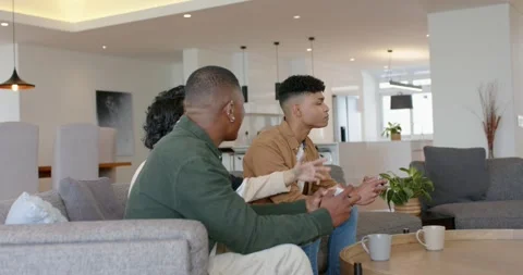 Game win causing diverse male friends raising fists, offering controller Stock Footage 335454413