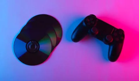 Gamepad and cd compact discs with pink blue neon light. Gaming, entertainment Stock Photos
