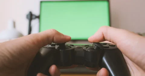 Gamepad in hands, playing console on the background of green monitor. Male hands Vídeos de archivo 202016172
