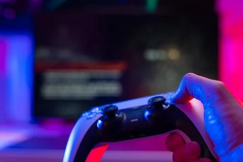 Gamepad in a man's hand on a technological background. Neon lighting. Close-u Stockfoto's