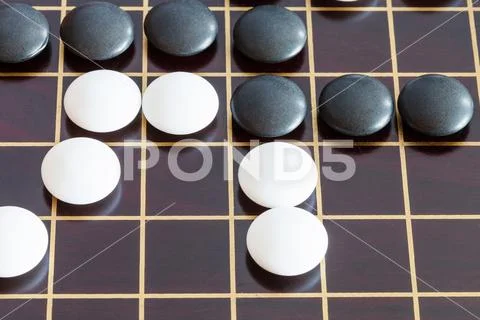 Gameplay of Go game on wooden board close up Stock Photos