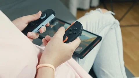 Gamer gripping nintendo switch 2 controllers, playing handheld video game Stock Footage 312441114
