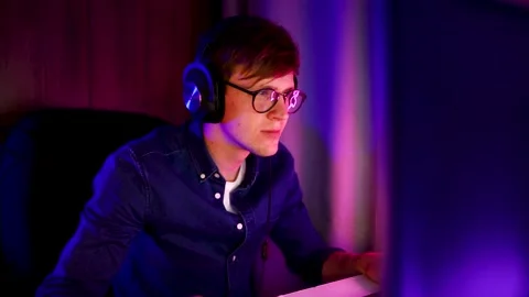 Gamer playing video games on a computer with headphones, winning games Stock Footage 143397566
