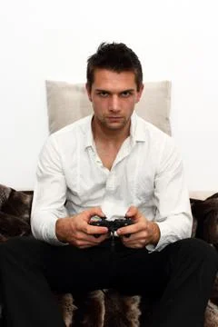Gamer sitting on couch with controller and playing Stock Photos
