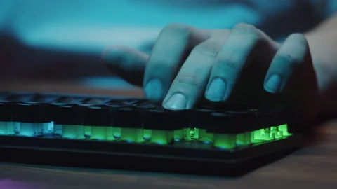 Gamer typing on backlight keyboard close-up, man playing video game. Male hands Видео 180550641