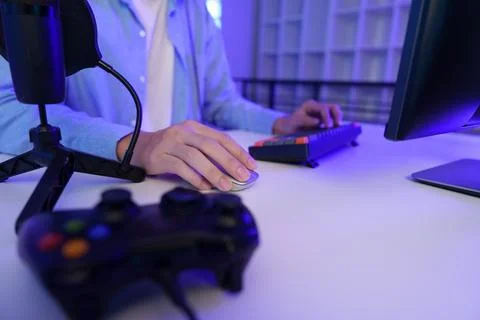 Gamer using computer mouse and keyboard at desk with controller for video gaming 写真素材