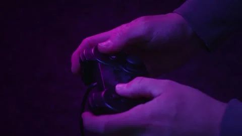 Gamer using a gaming controller fast and aggressively in subdued light Stock Footage 241448280