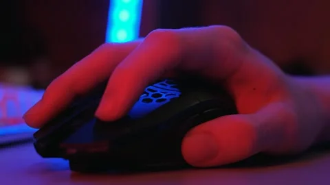 A gamer's hand uses a computer mouse in neon light, close-up Video stock 263366329