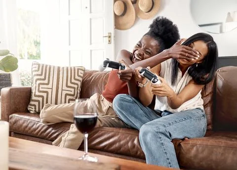 Gaming, cheating and friends with controller on sofa, playing together and Stock Photos