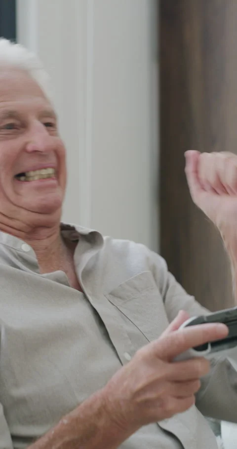 Gaming, controller and winner with old man on sofa in home for esports, online Stock Footage 335197718