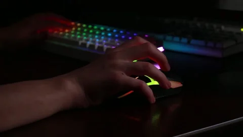 Gaming setup with hand on mouse and illuminated keyboard in dark room Stock Footage 320411998