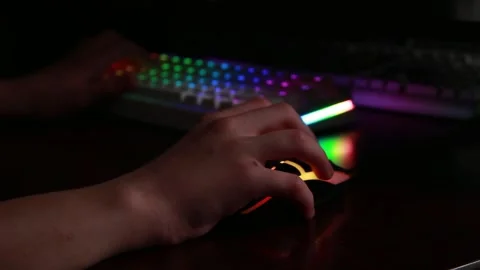 Gaming setup with illuminated mouse and keyboard in dark room focus on hand Stock Footage 320411970
