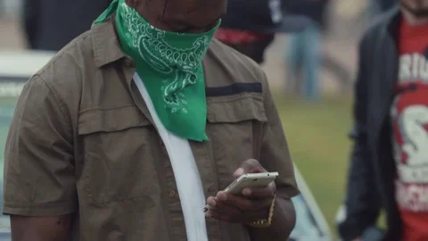 Gangster black man using smart phone texting at crowded event Stock Footage 78857541