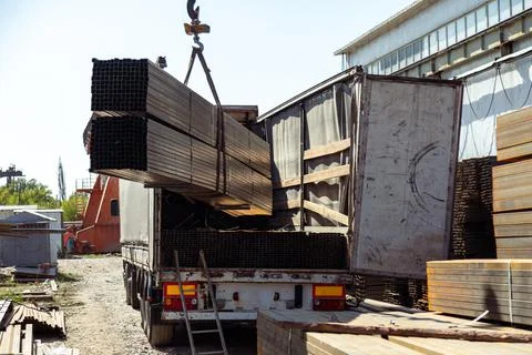 Gantry crane loading stack of metal pipes into truck Stockfoto's