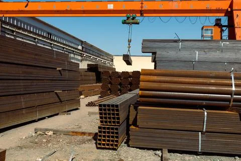Gantry crane transporting stack of metal pipes Foto stock