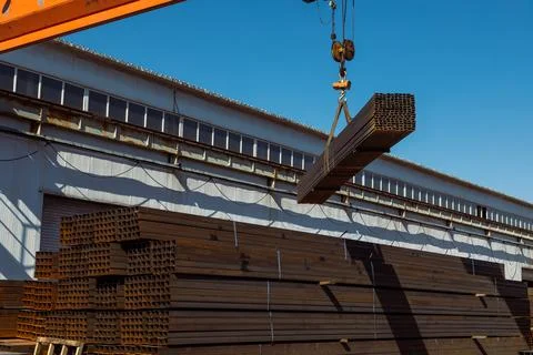 Gantry crane transporting stack of metal pipes Stock Photos