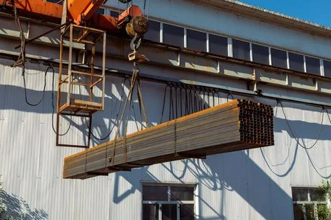 Gantry crane transporting stack of metal pipes Stock Photos