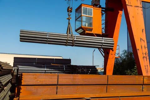 Gantry crane transporting stack of metal pipes Stockfoto's